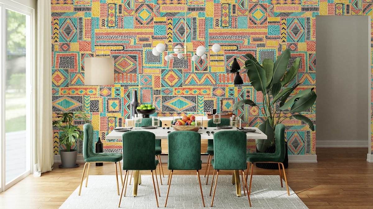 Bohemian geometric wallpaper in vibrant pastel, dining room features green velvet chairs, wood flooring.