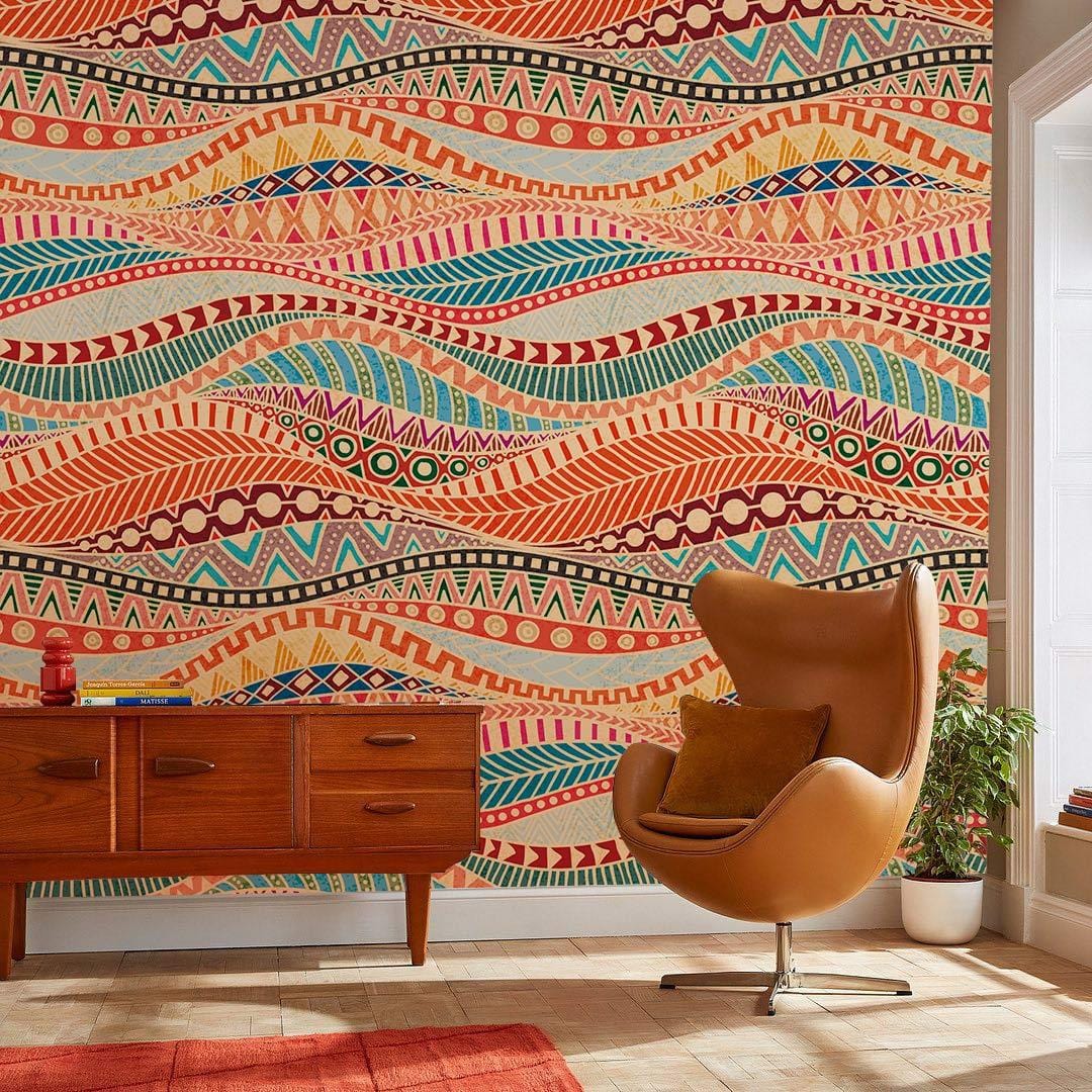 Vibrant Tribal Bohemian Multicolour Wallpaper in artistic living room with brown swivel chair, wooden sideboard.