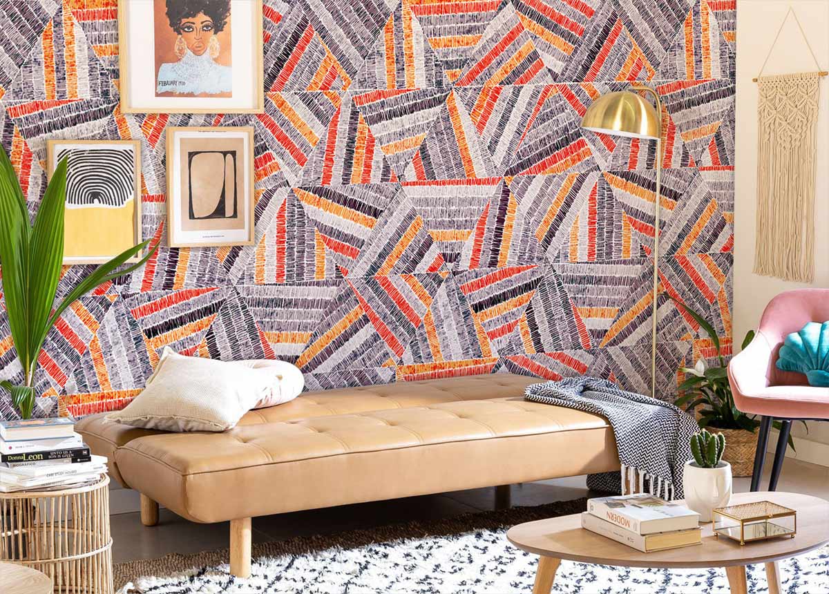Vibrant geometric wallpaper in orange and grey; modern living room with beige sofa, artwork, cosy decor.