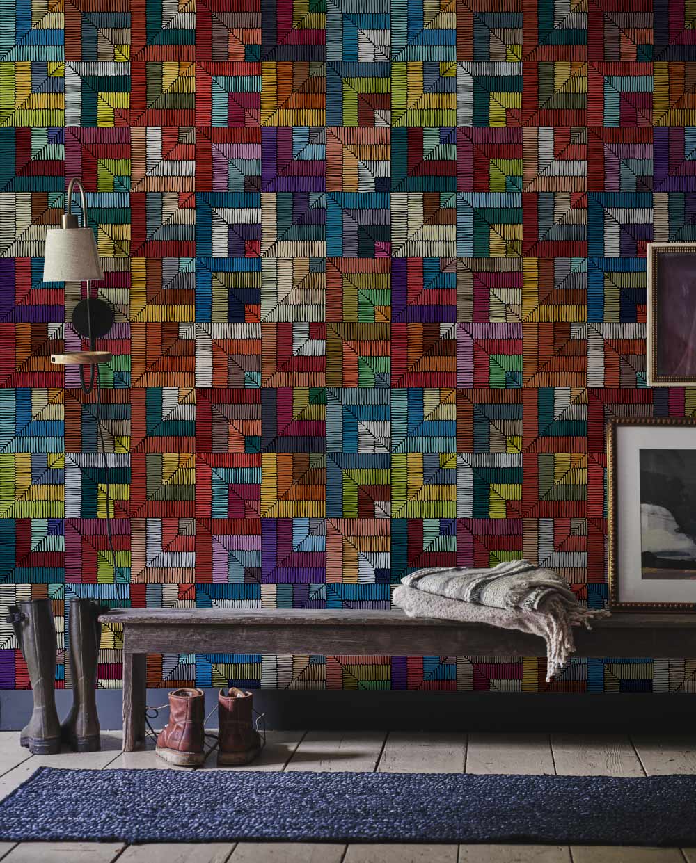 Vibrant geometric mosaic wallpaper in a modern room with dark wood bench, grey tile flooring, and art.