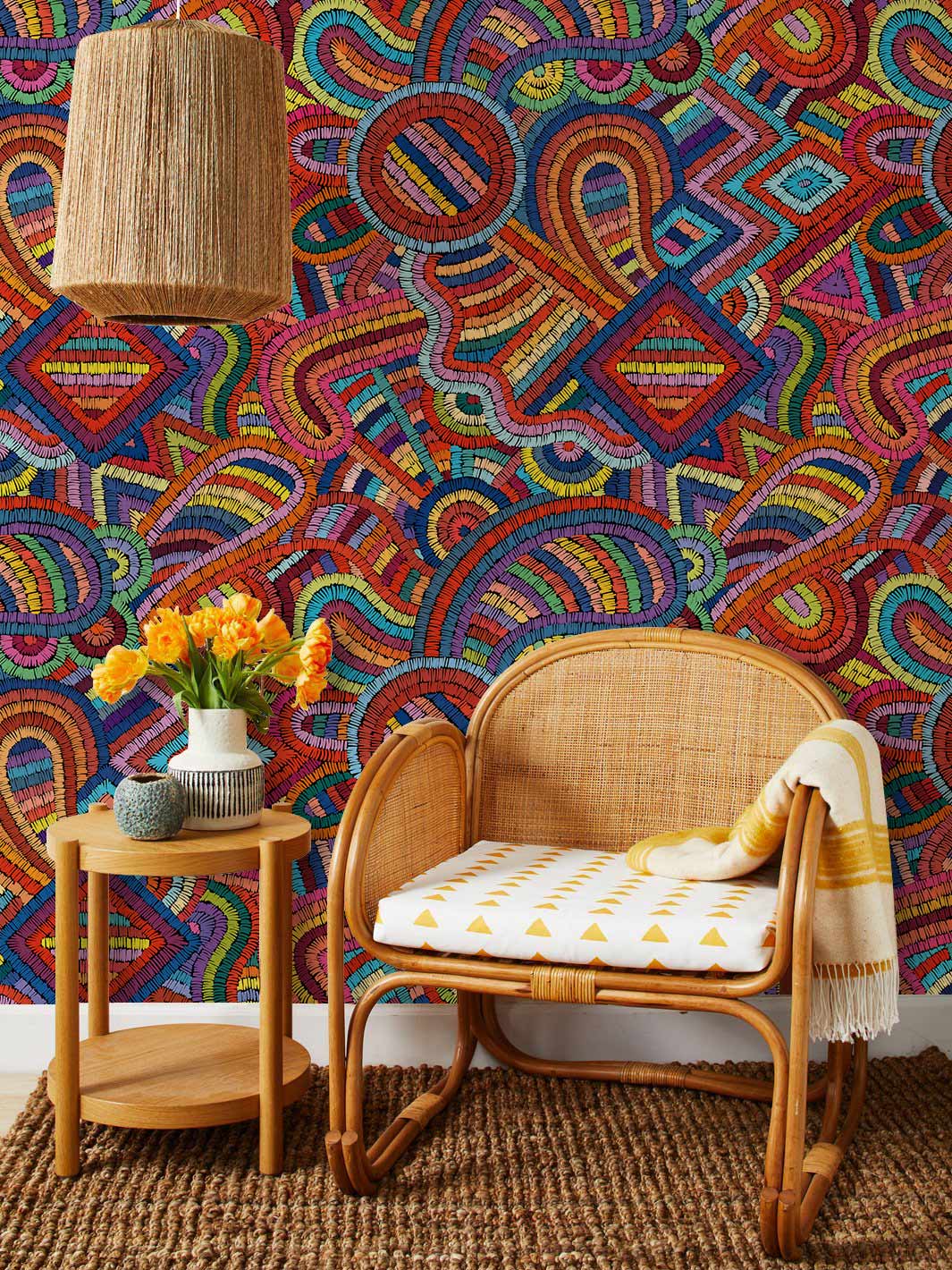 Rattan chair, woven lampshade, vibrant geometric mural wallpaper in colourful room with natural decor.