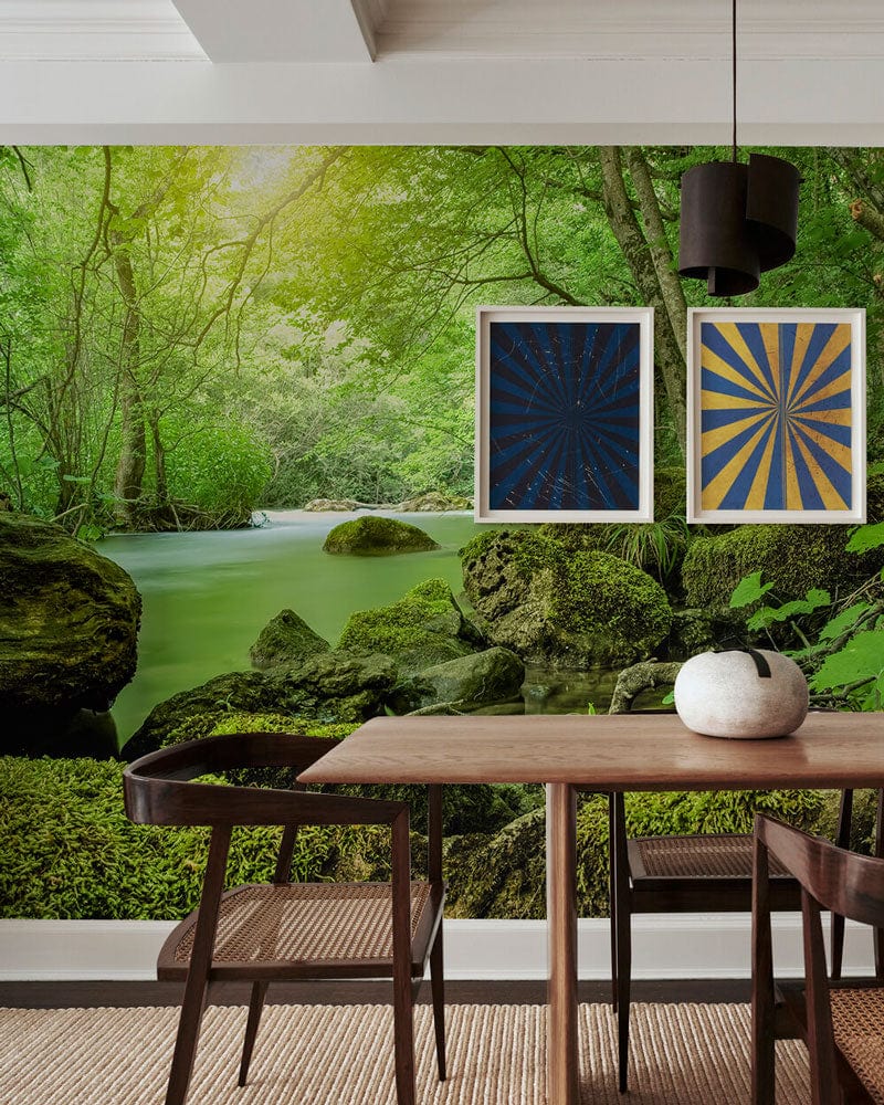 Modern dining room with Serene Green Forest Stream mural wallpaper, wooden table, stylish chairs, and artwork.