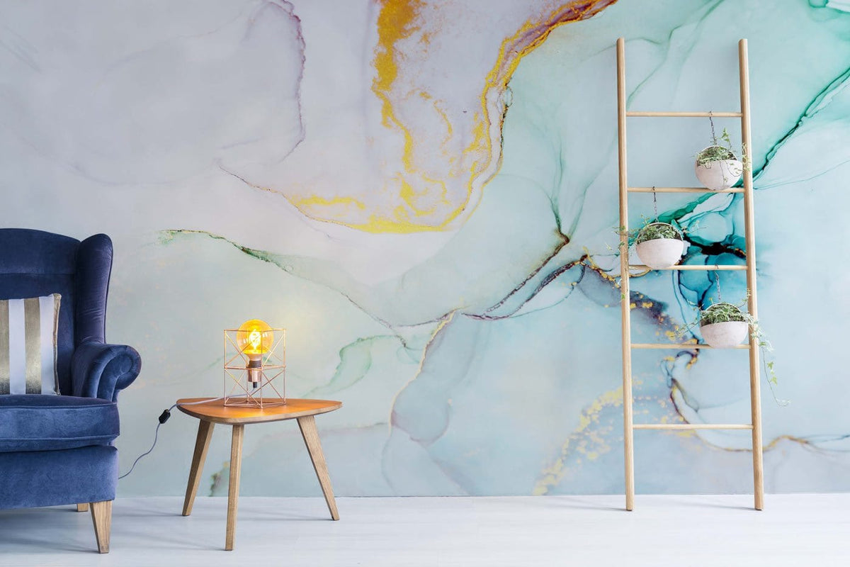 Aqua and gold abstract wallpaper in modern living room, featuring blue velvet armchair, wood table.