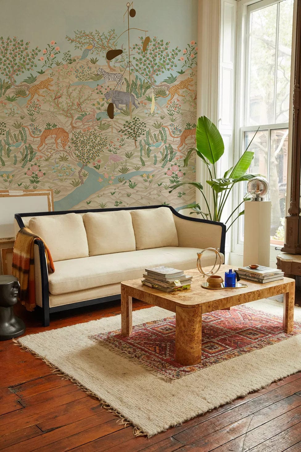 Exotic jungle mural wallpaper, soft pastel tones, beige sofa, wooden coffee table, living room setting.