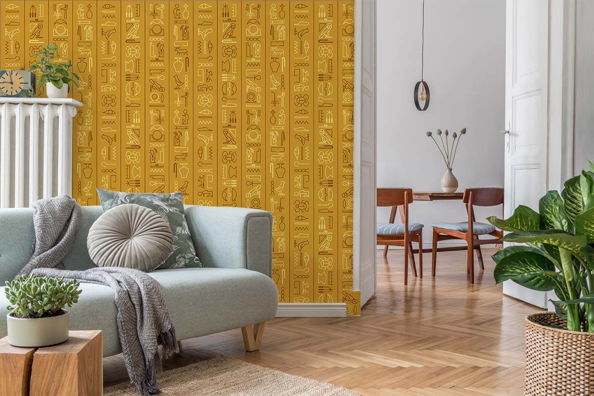 Ancient Egyptian gold hieroglyphics wallpaper with light blue sofa, wooden flooring, dining area view.