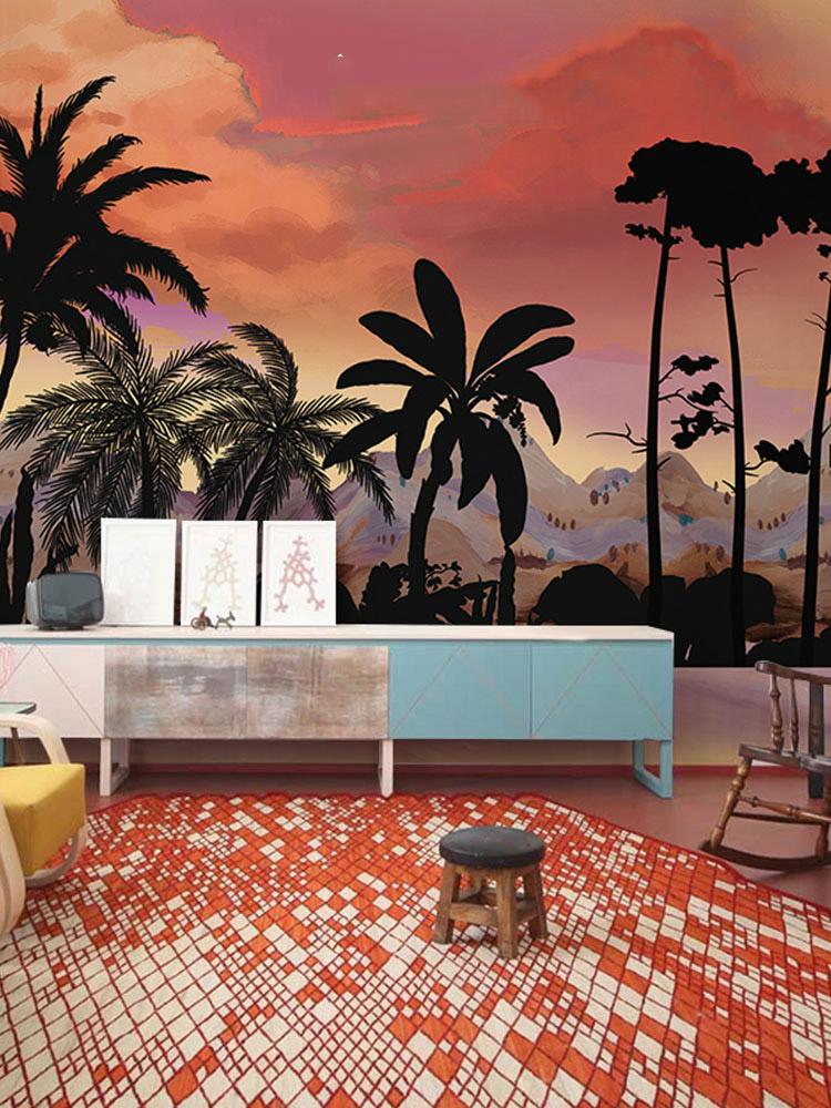 Tropical sunset mural wallpaper in vibrant room with patterned rug, sideboard, and eclectic chair.