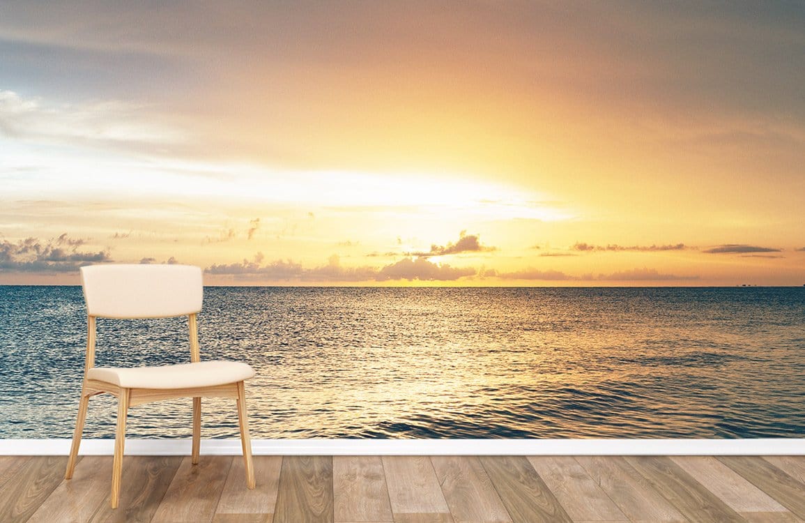 Golden Horizon Ocean Sunset Mural Wallpaper with beige chair, wood flooring, serene coastal landscape decor.