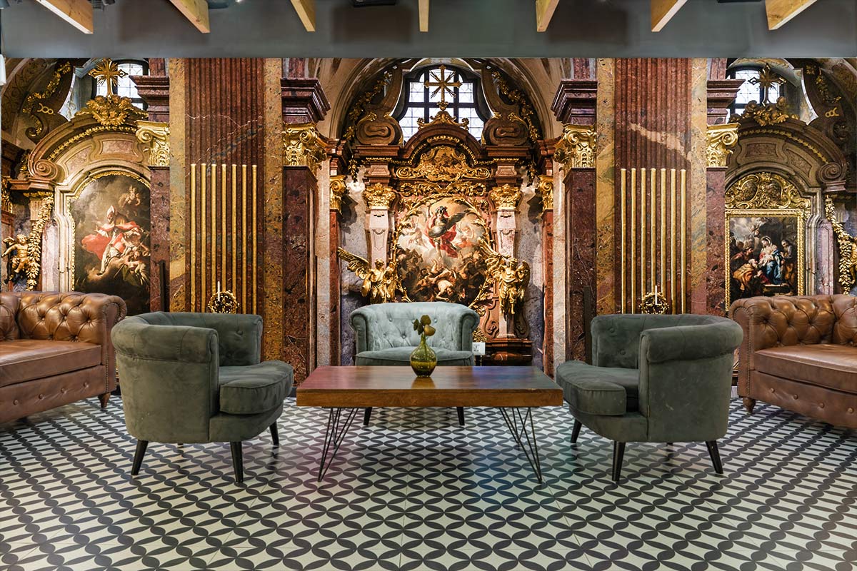 Luxurious Baroque mural wallpaper, earthy tones, upholstered sofas, patterned floor, elegant lounge setting.