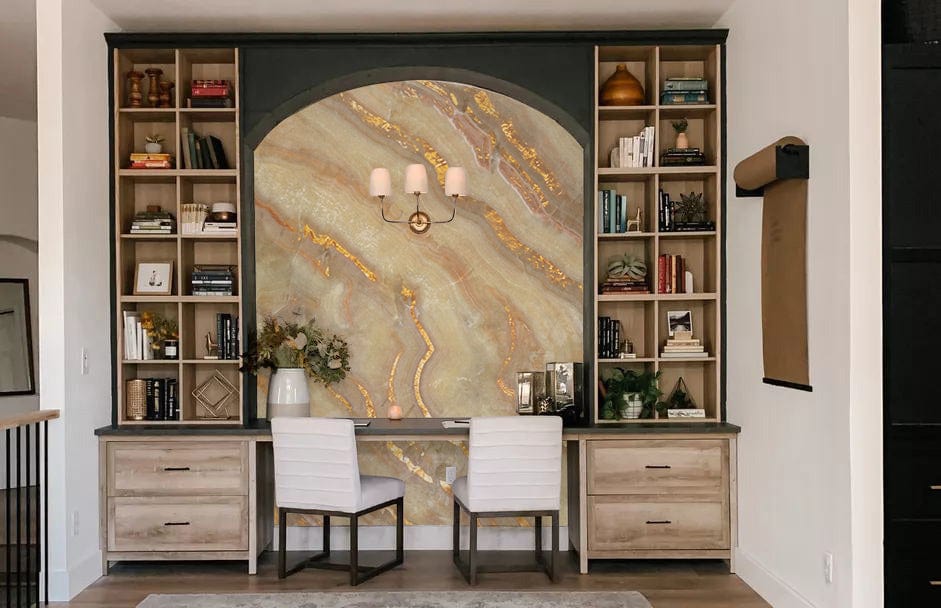 Elegant study with golden marble effect luxury wallpaper, earthy tones, built-in shelves, two white chairs.