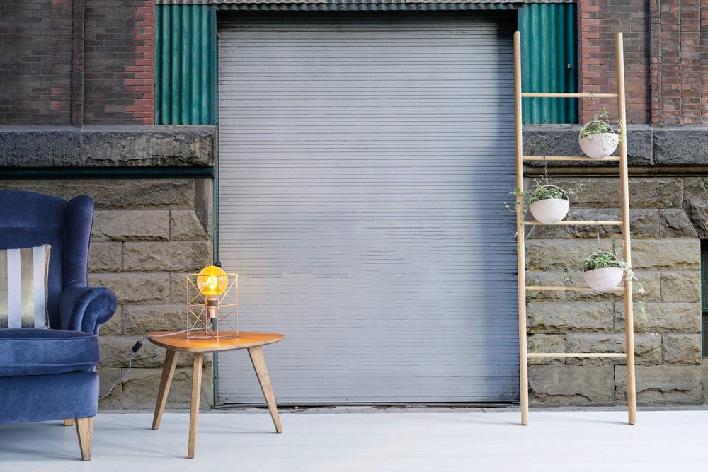 Industrial Urban Grey Stone Metal Doorway Mural Wallpaper in room with navy sofa and wooden ladder.
