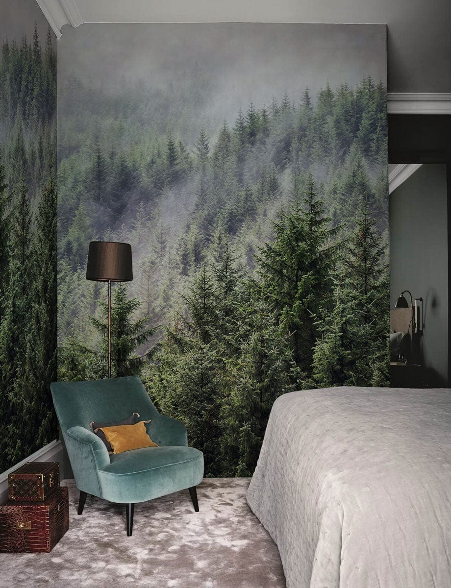 Misty forest mural wallpaper in serene bedroom with teal armchair, grey bedding, and floor lamp.