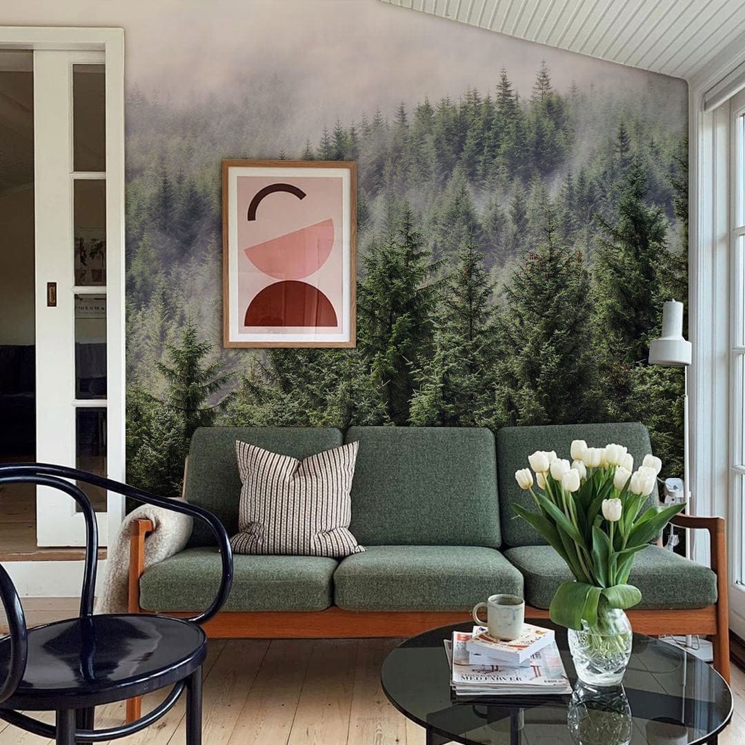Misty Forest Green Pine Mural Wallpaper in cosy living room with green sofa and wooden flooring.