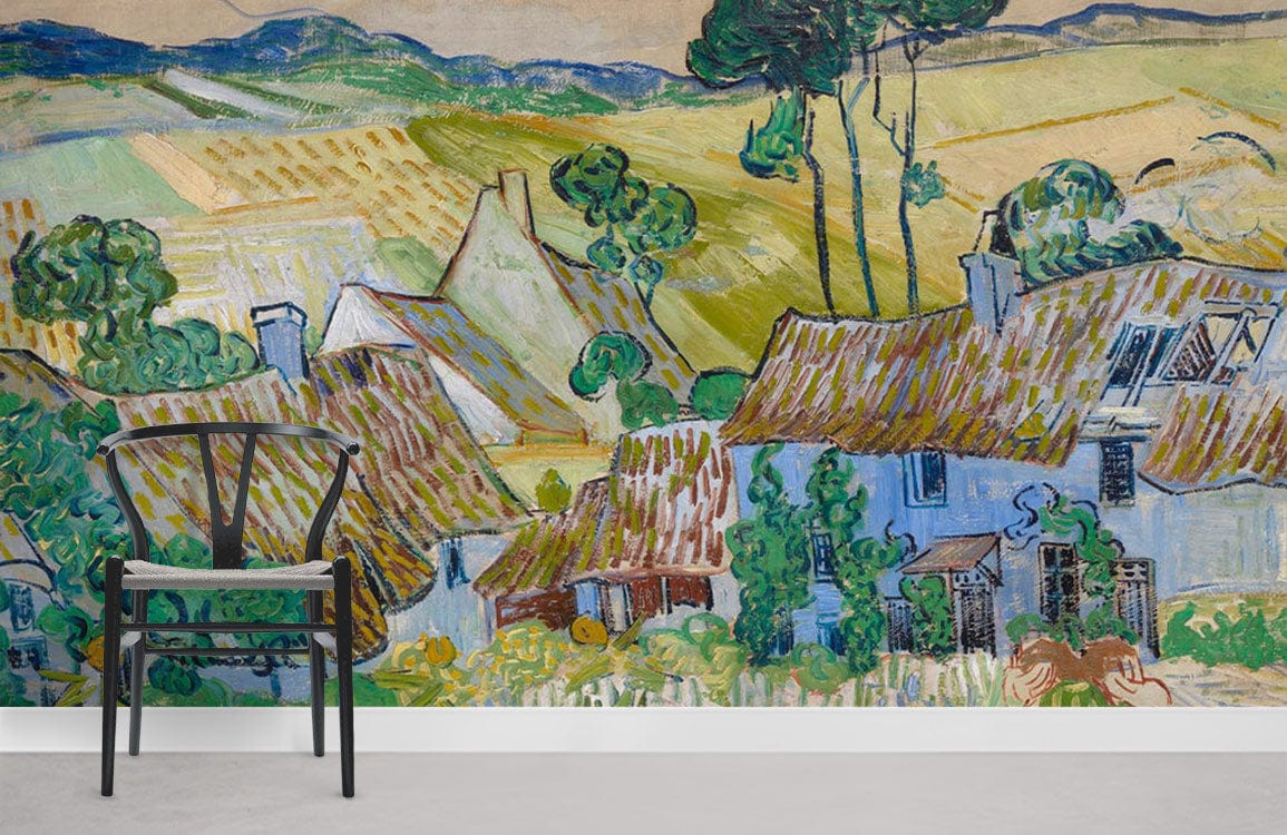 Charming mural wallpaper featuring rustic cottages, vibrant blues and greens, with modern chair on grey floor.