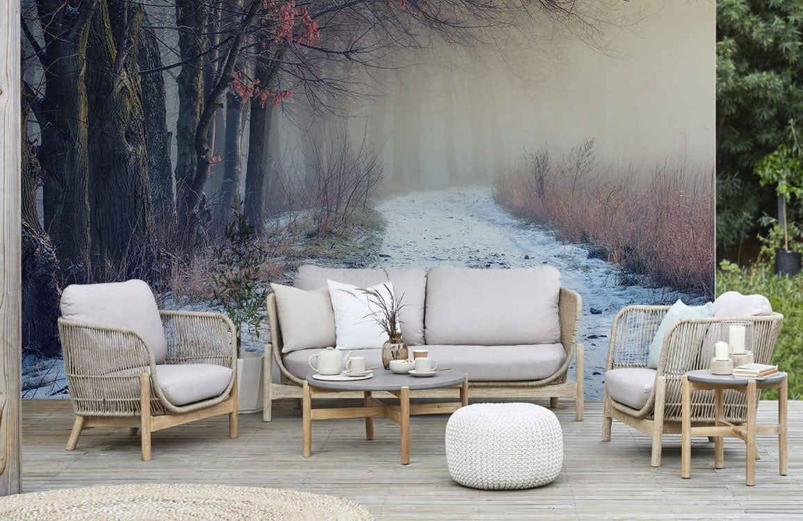 Winter Forest Path Mural Wallpaper, serene misty landscape, beige wicker furniture, wooden flooring, garden setting.