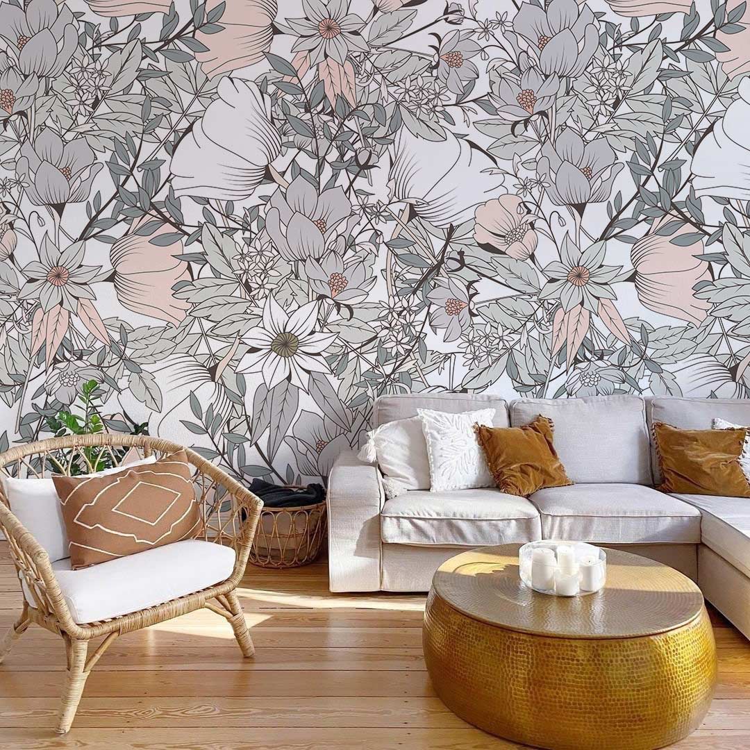 Elegant pastel botanical wallpaper in neutral tones, beige corner sofa, golden coffee table, wicker chair.