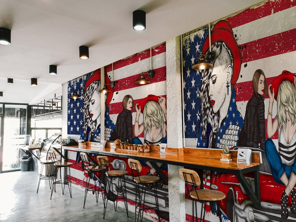 Retro American pop art mural wallpaper, bold colours, vintage car, cafe setting with stools, industrial decor.