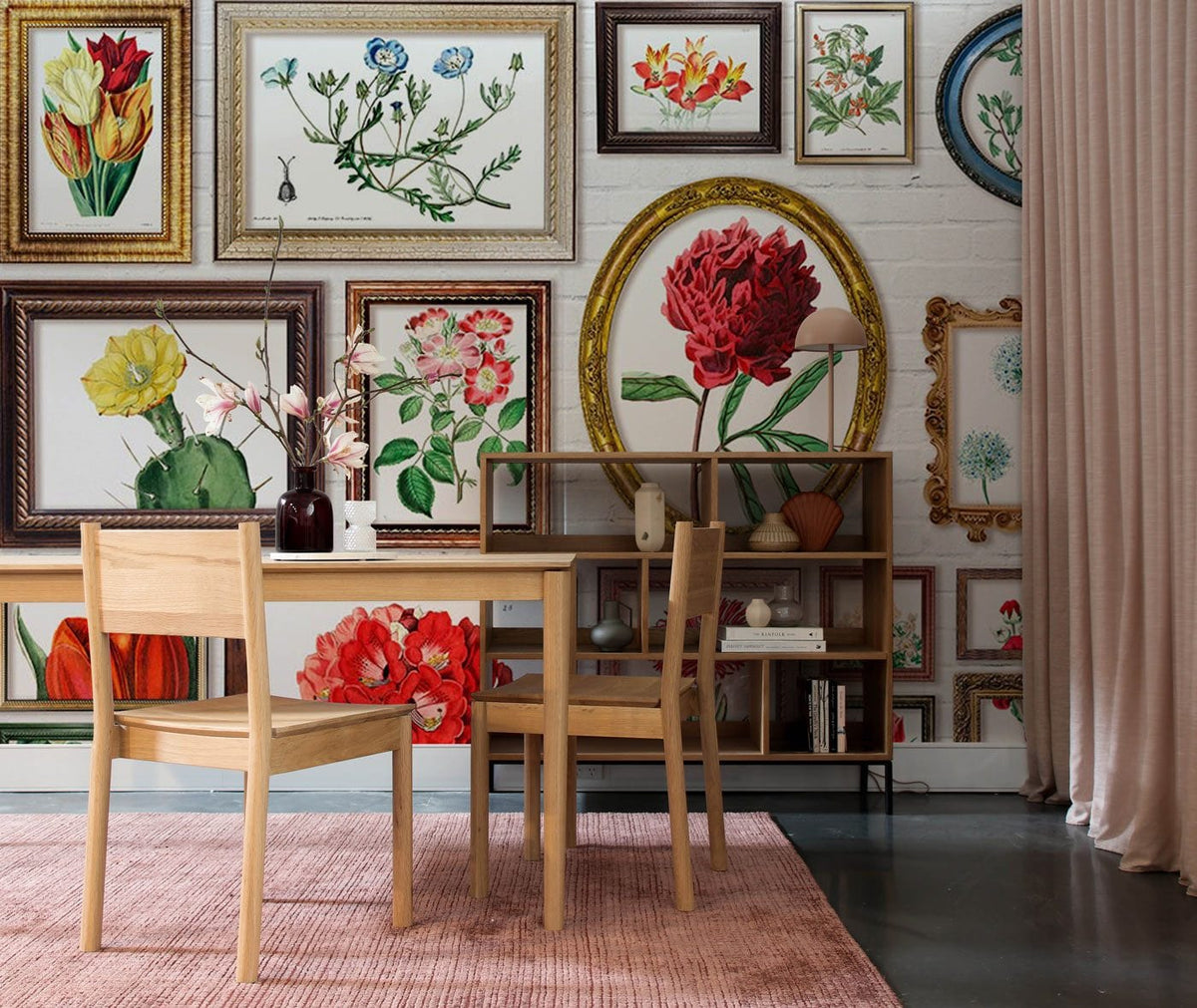 Vintage floral mural wallpaper, framed botanical prints, wooden chairs, pink rug, bookshelf, concrete floor.