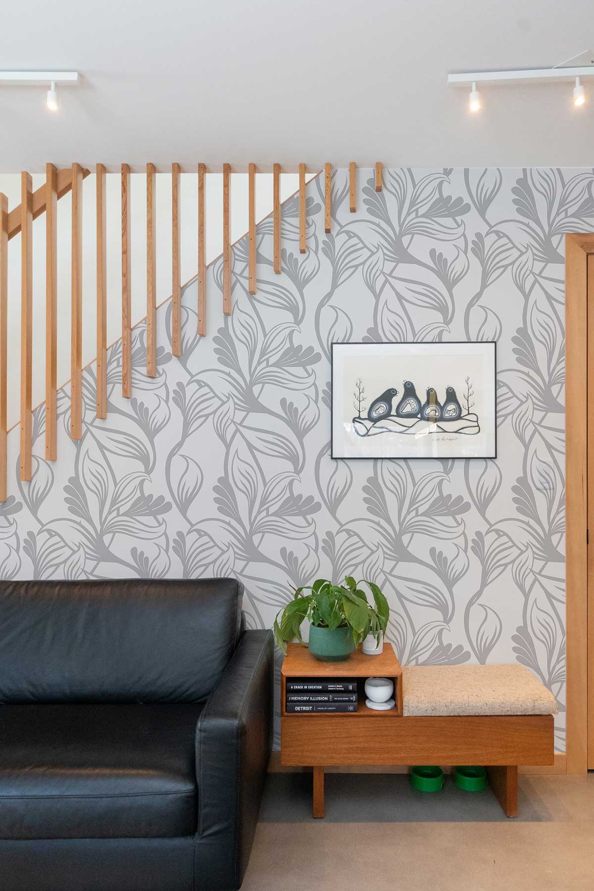 Elegant grey botanical wallpaper, stylish interior with black leather sofa, wooden elements, modern artwork.