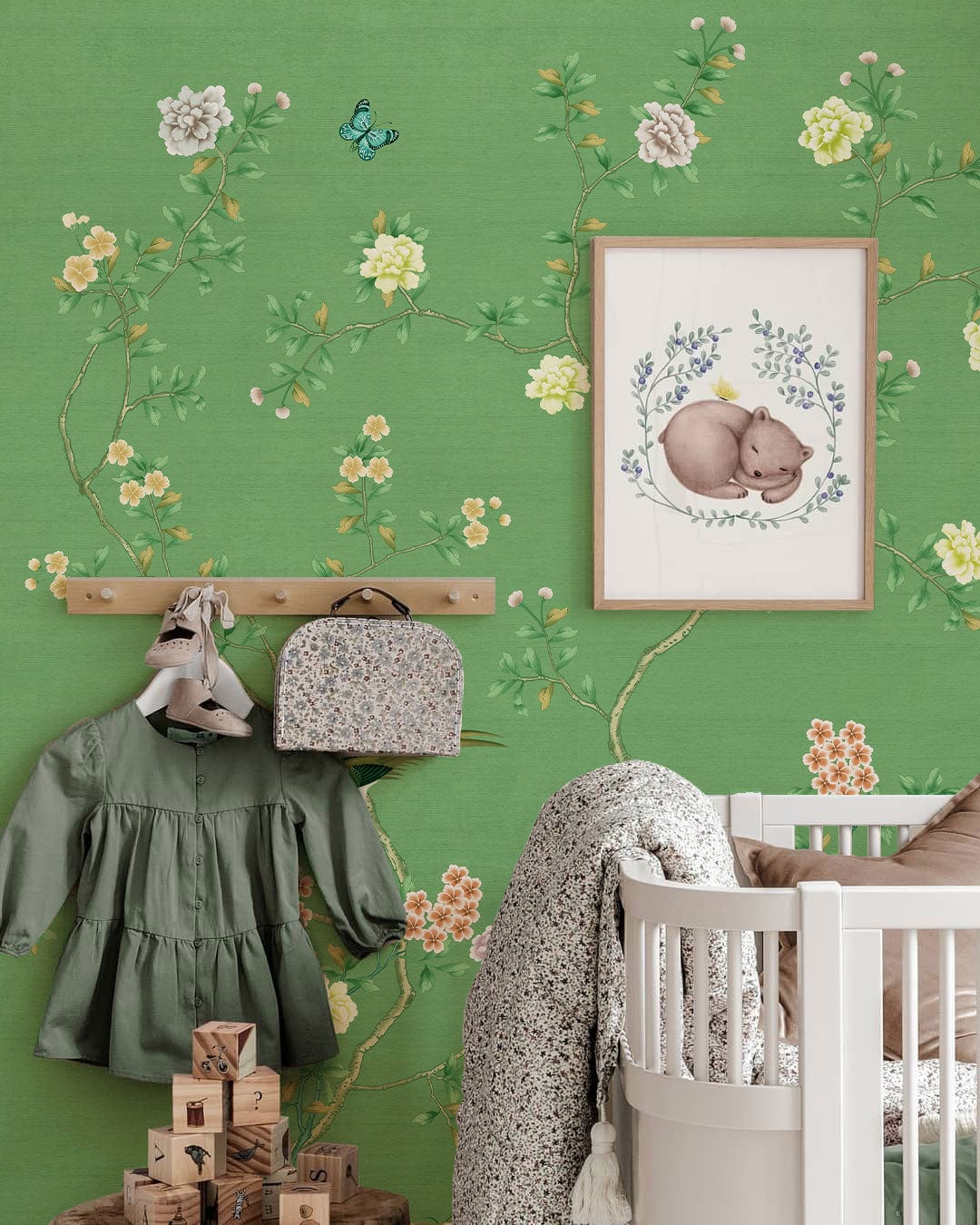 Elegant green floral wallpaper with birds, nursery room decor, white crib, wooden coat rack.