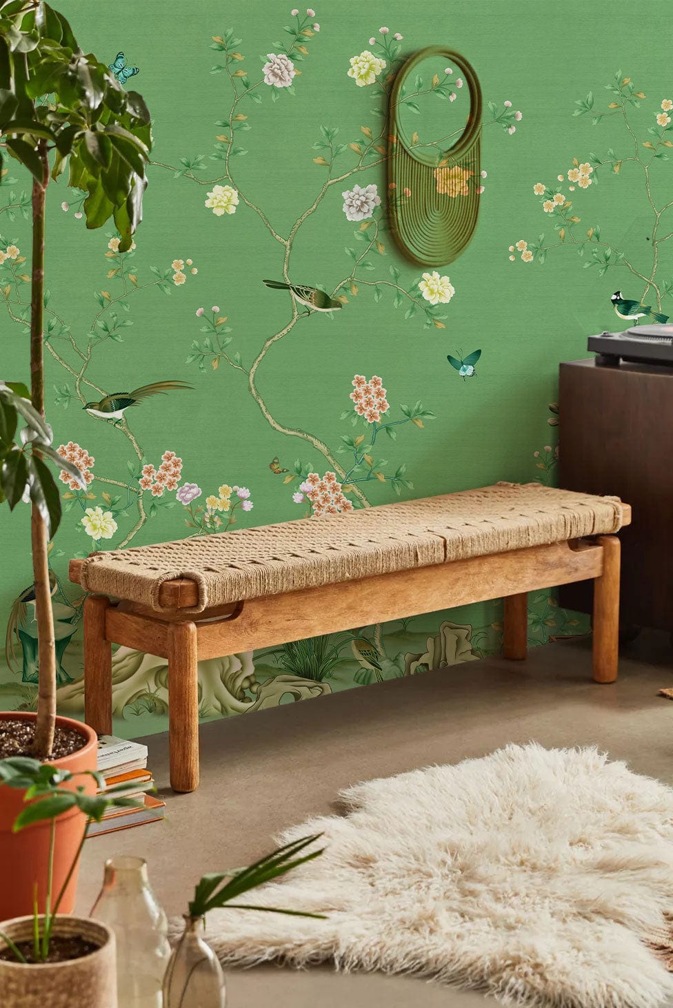 Elegant green floral wallpaper in cosy room with wooden bench, cream rug, and potted plant.