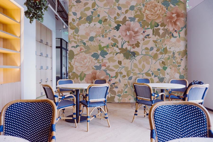 Elegant vintage floral wallpaper in dining room with blue chairs, light wooden flooring, minimal decor.