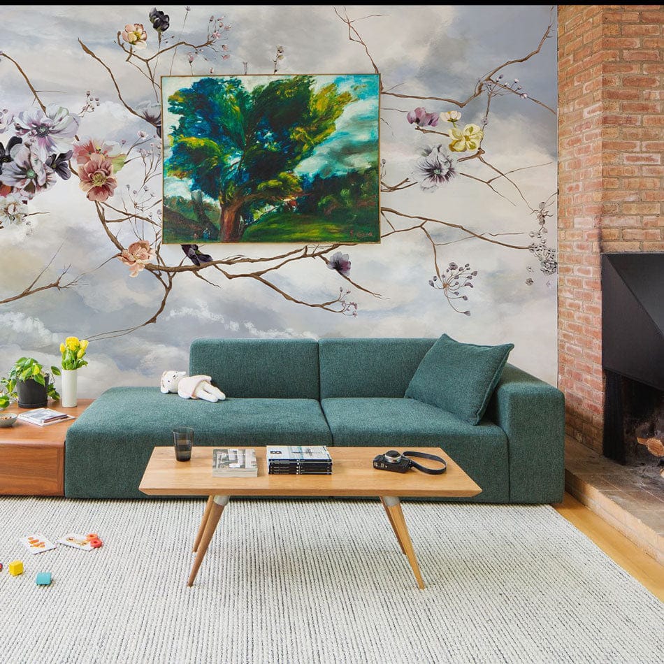 Floral mural wallpaper with green sofa, brick wall, and rug; serene living room setting.