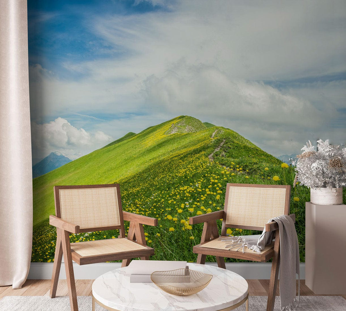 Wallpaper mural showcasing serene green mountain pasture with yellow wildflowers, featuring natural wooden chairs.