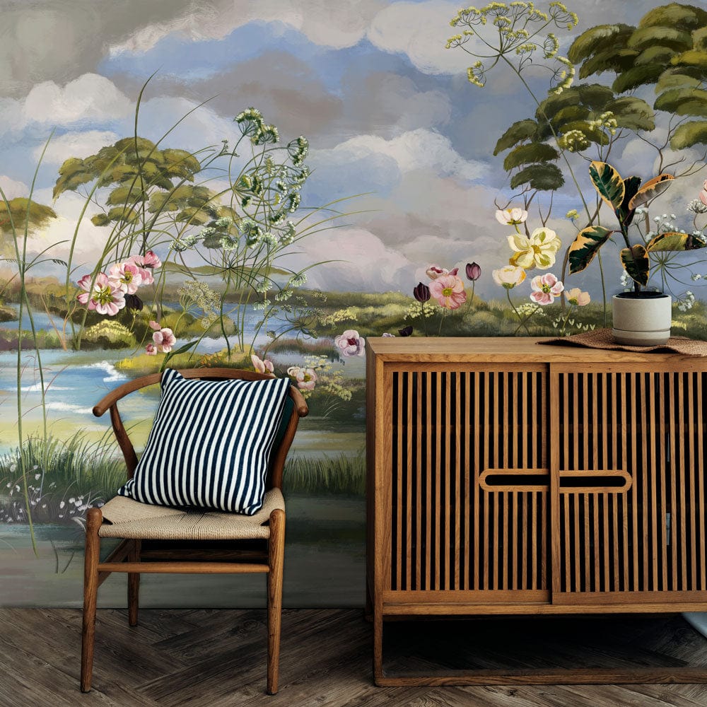 Pastoral Haven mural wallpaper with floral tones, wooden sideboard, striped cushion on chair, wooden flooring.