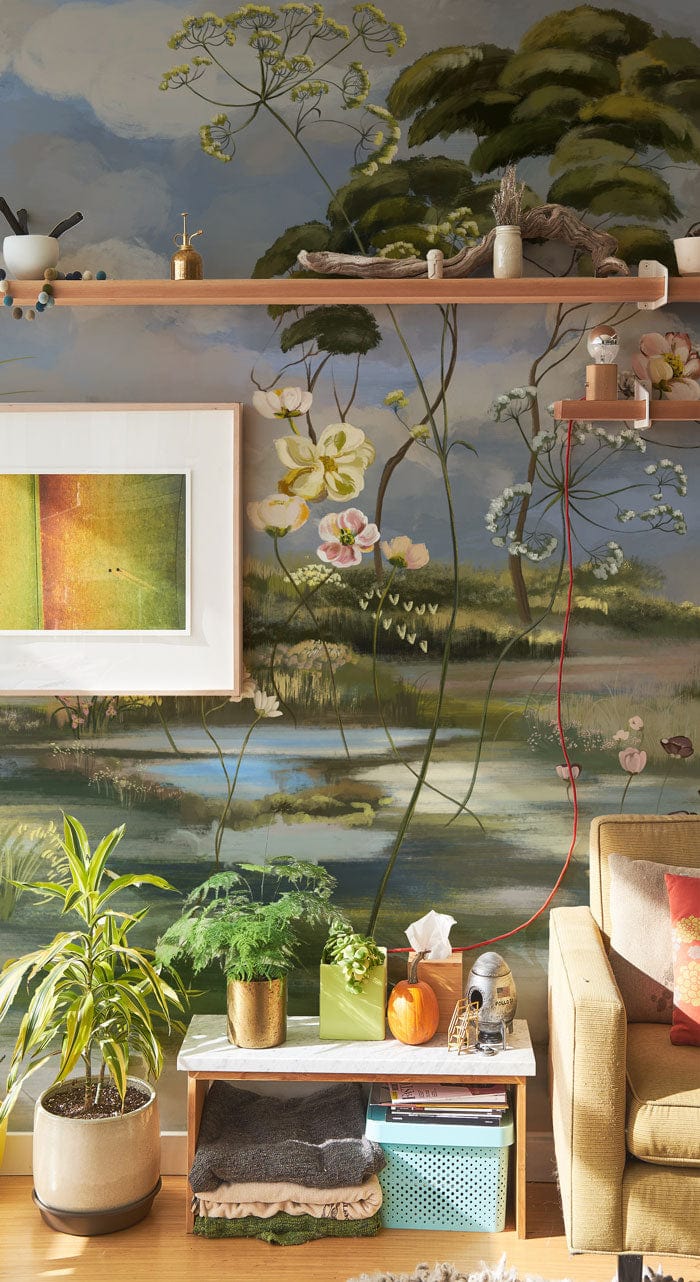 Pastoral Haven mural wallpaper with floral design, pastel tones, rustic wooden shelves, and modern beige sofa.