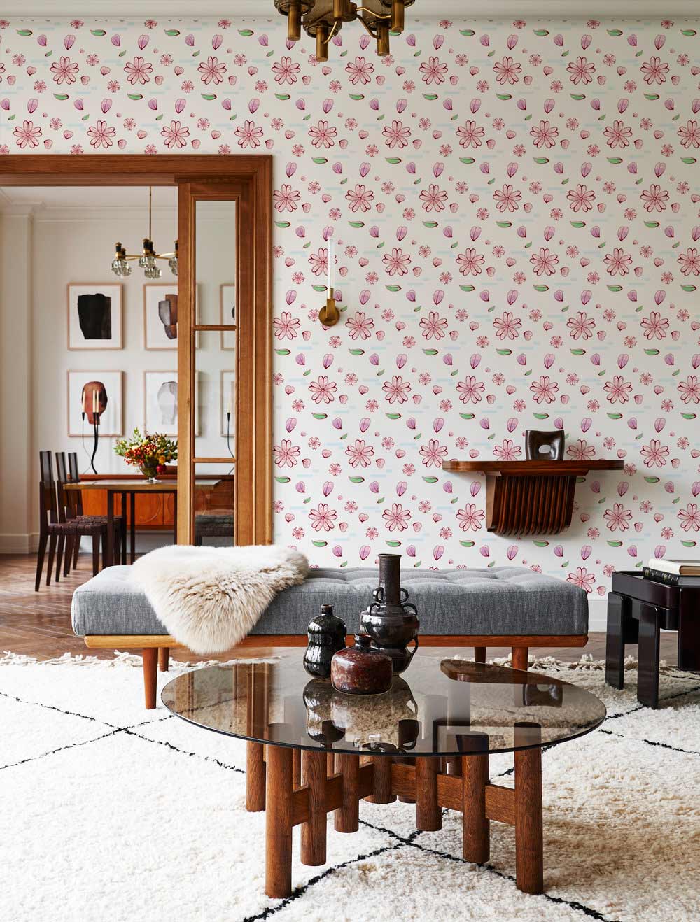 Pink floral blossom wallpaper in vintage style with grey bench, glass table, and white rug.