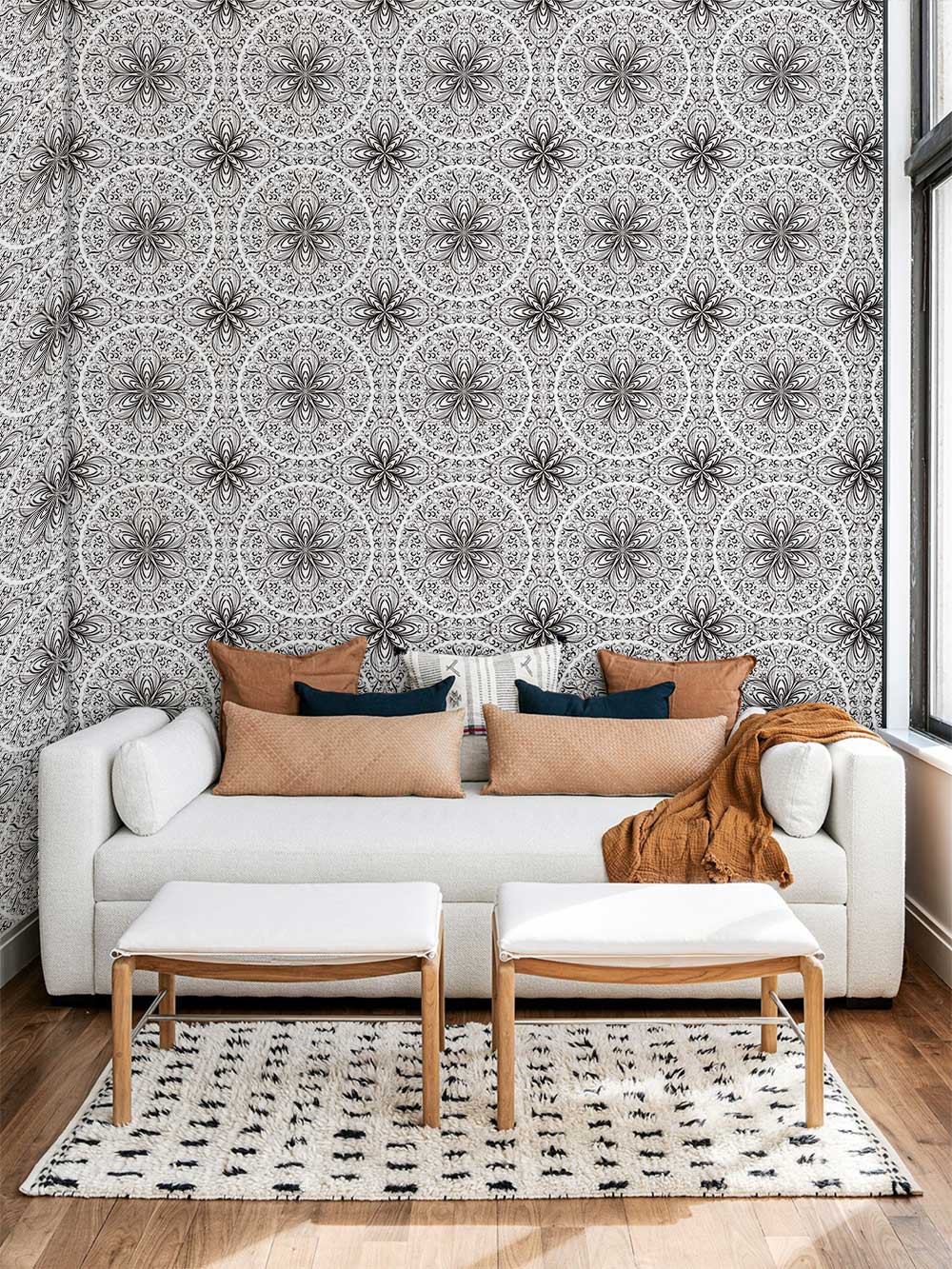Elegant monochrome mandala wallpaper in stylish living room with white sofa, wooden flooring, patterned rug.