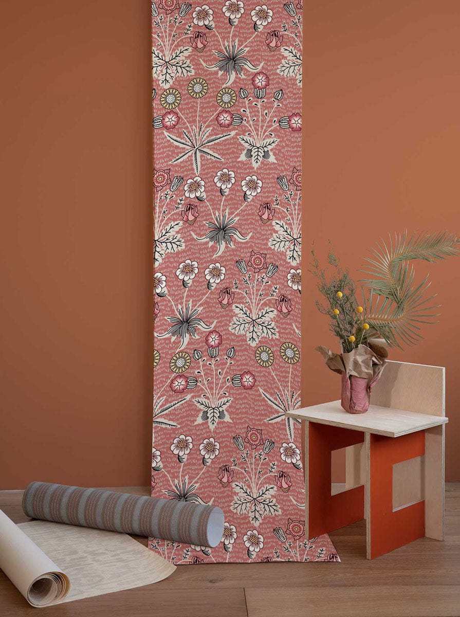 Vintage floral wallpaper, red and green botanical design, wooden chair, neutral flooring, warm wall colour.