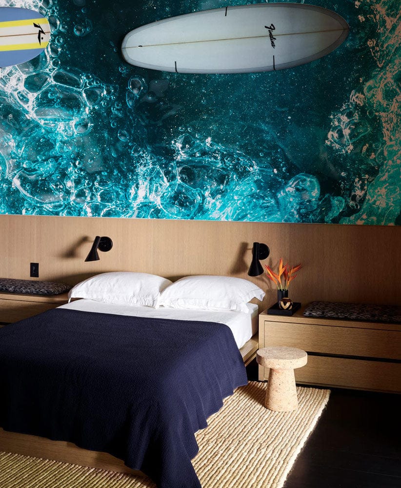 Bedroom features Oceanic Teal Abstract Bubbles mural, dark bedding, wooden accents, stylish lighting, woven rug.