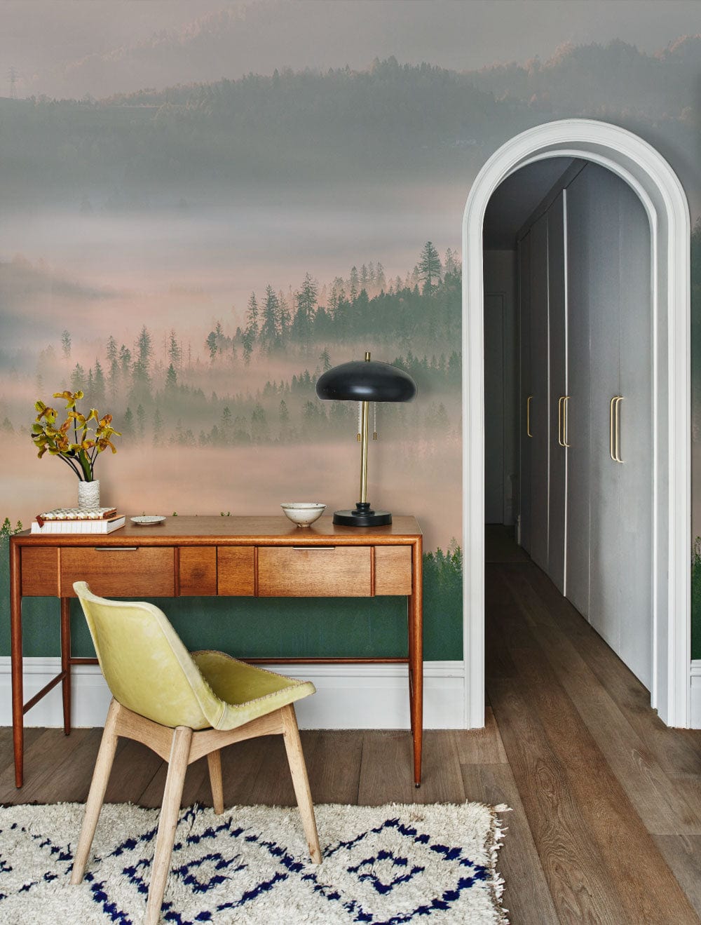 Serene Misty Mountain wallpaper with vintage desk, pastel chair, arched doorway, and stylish wooden flooring.