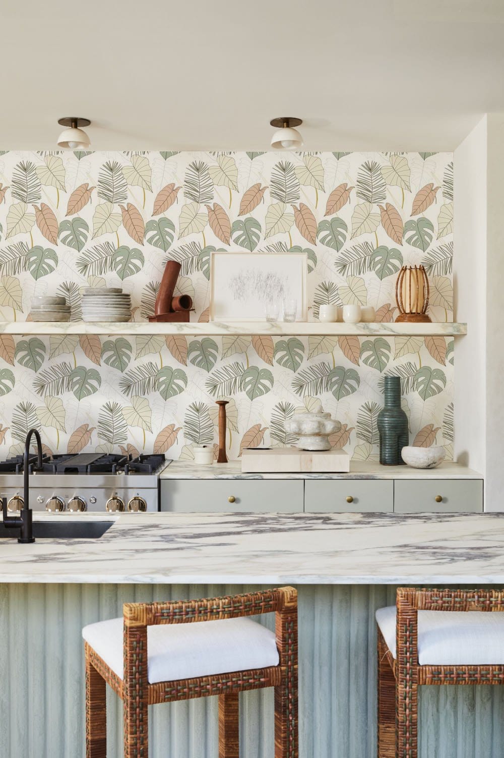 Botanical Bliss Tropical Leaf Wallpaper in earthy tones, kitchen setting with wooden bar stools.