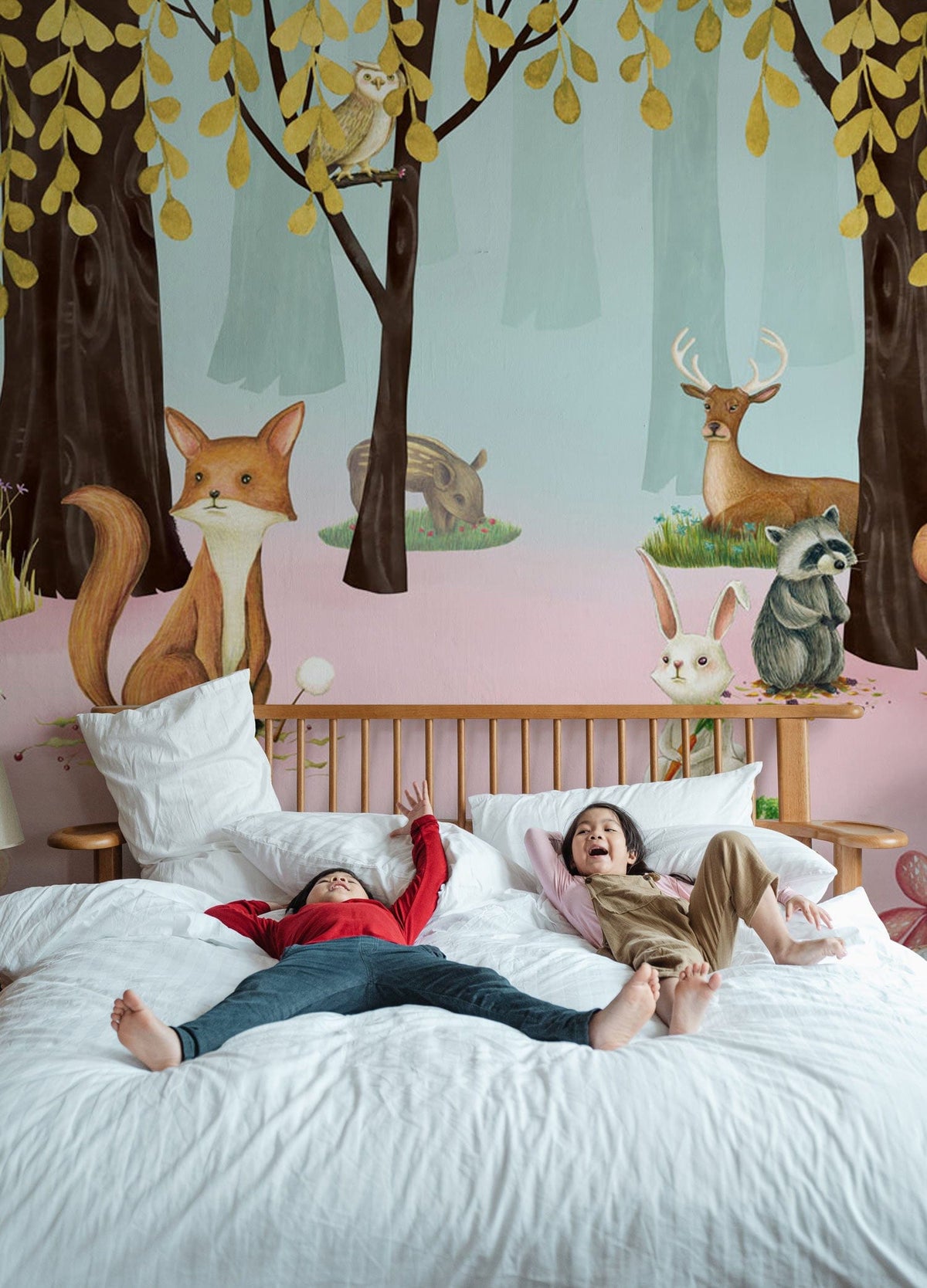 Children's bedroom with whimsical woodland creatures mural wallpaper in soft pastel colours, wooden bed.