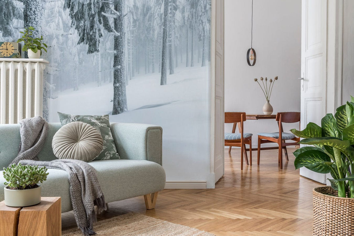 Snowy Winter Forest Mural Wallpaper in white, grey. Elegant grey sofa. Wooden flooring. Living room decor.