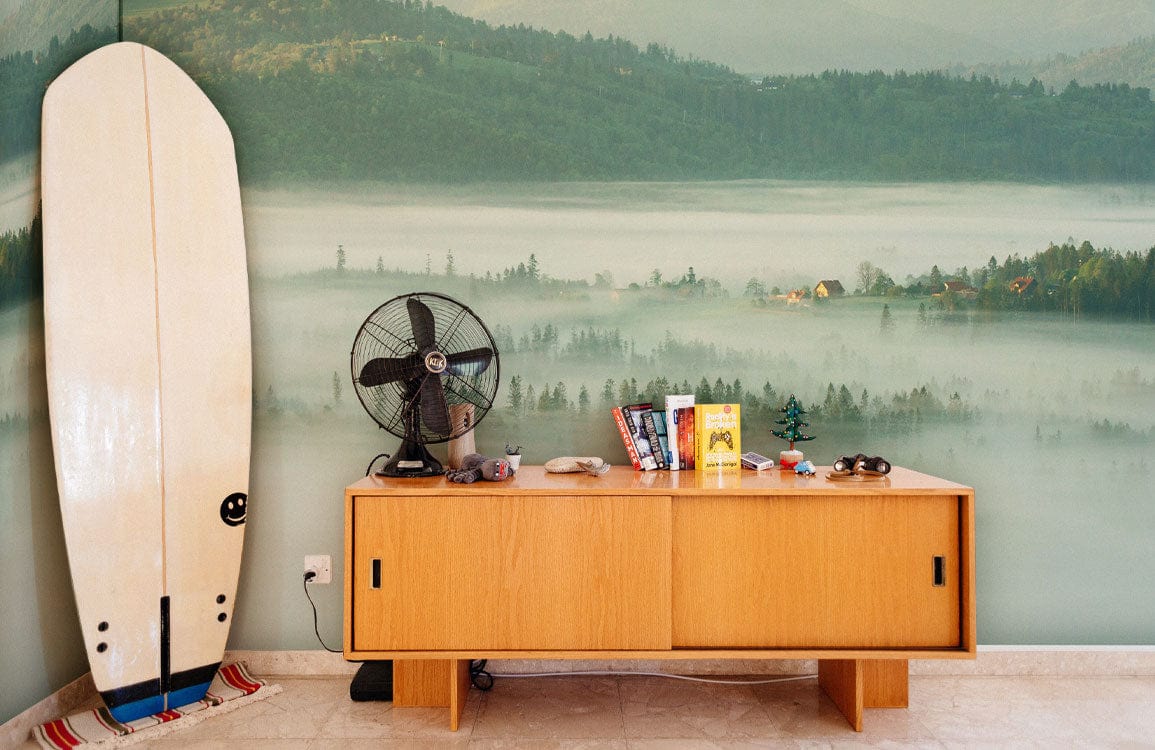 Misty Mountain Morning Mural Wallpaper, serene landscape; wooden sideboard, vintage fan, surfboard; tiled flooring.