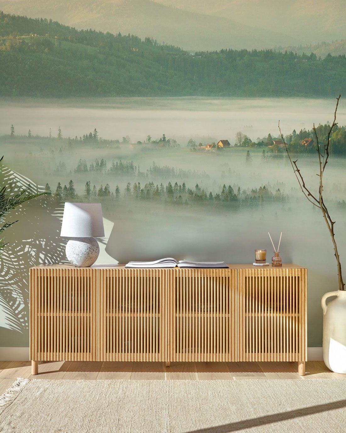 Misty Mountain Morning Mural Wallpaper with neutral sideboard, misty green landscape, and serene decor elements.