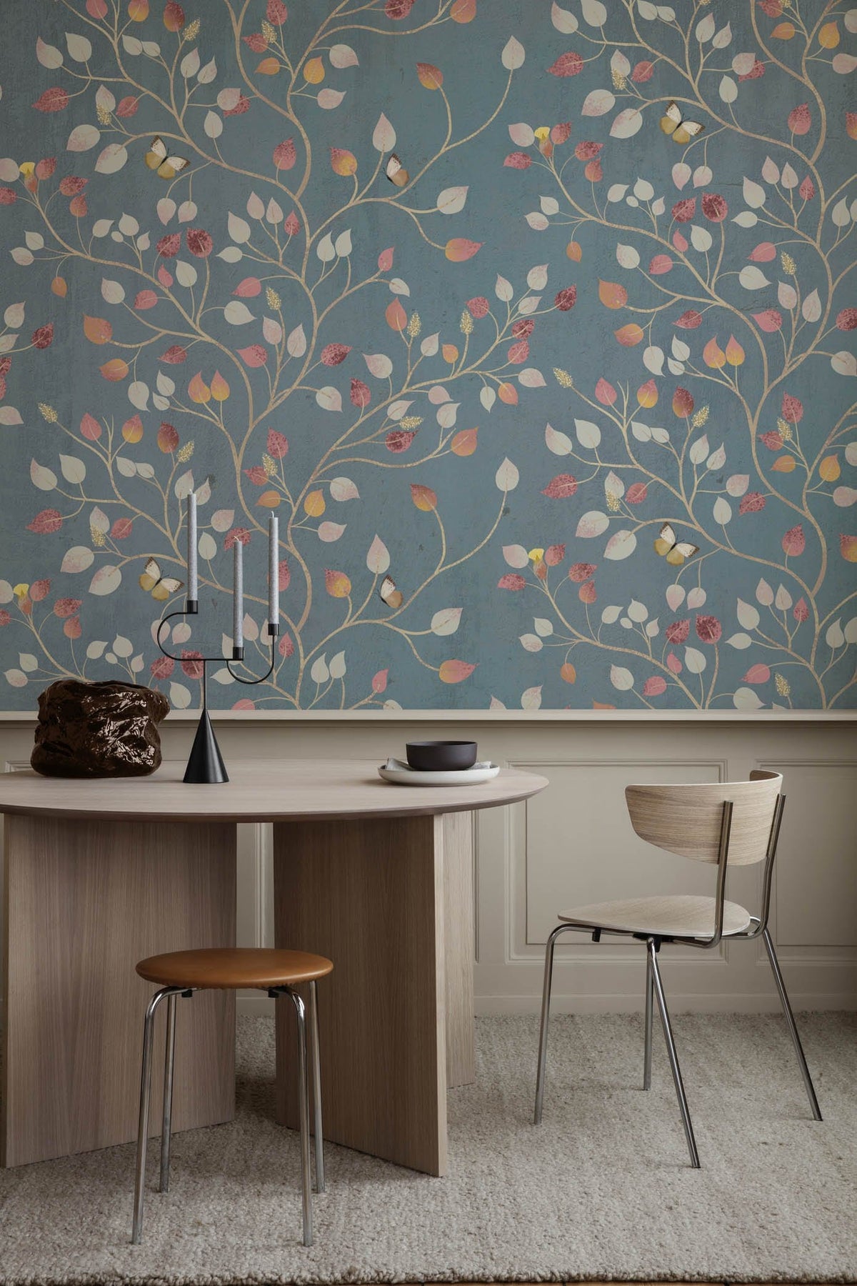Vintage blue floral wallpaper with autumn leaves, wooden table, modern chair, beige rug, dining room.