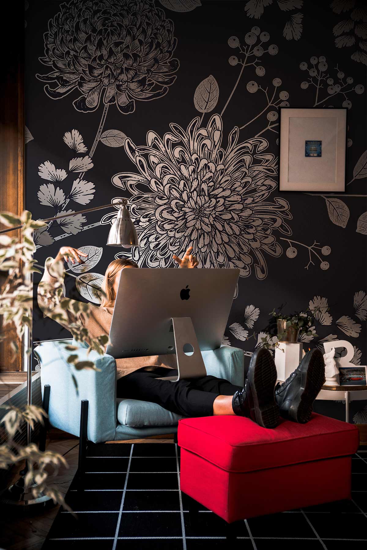 Elegant grey botanical floral wallpaper with butterfly design, blue armchair, red footstool, black flooring.