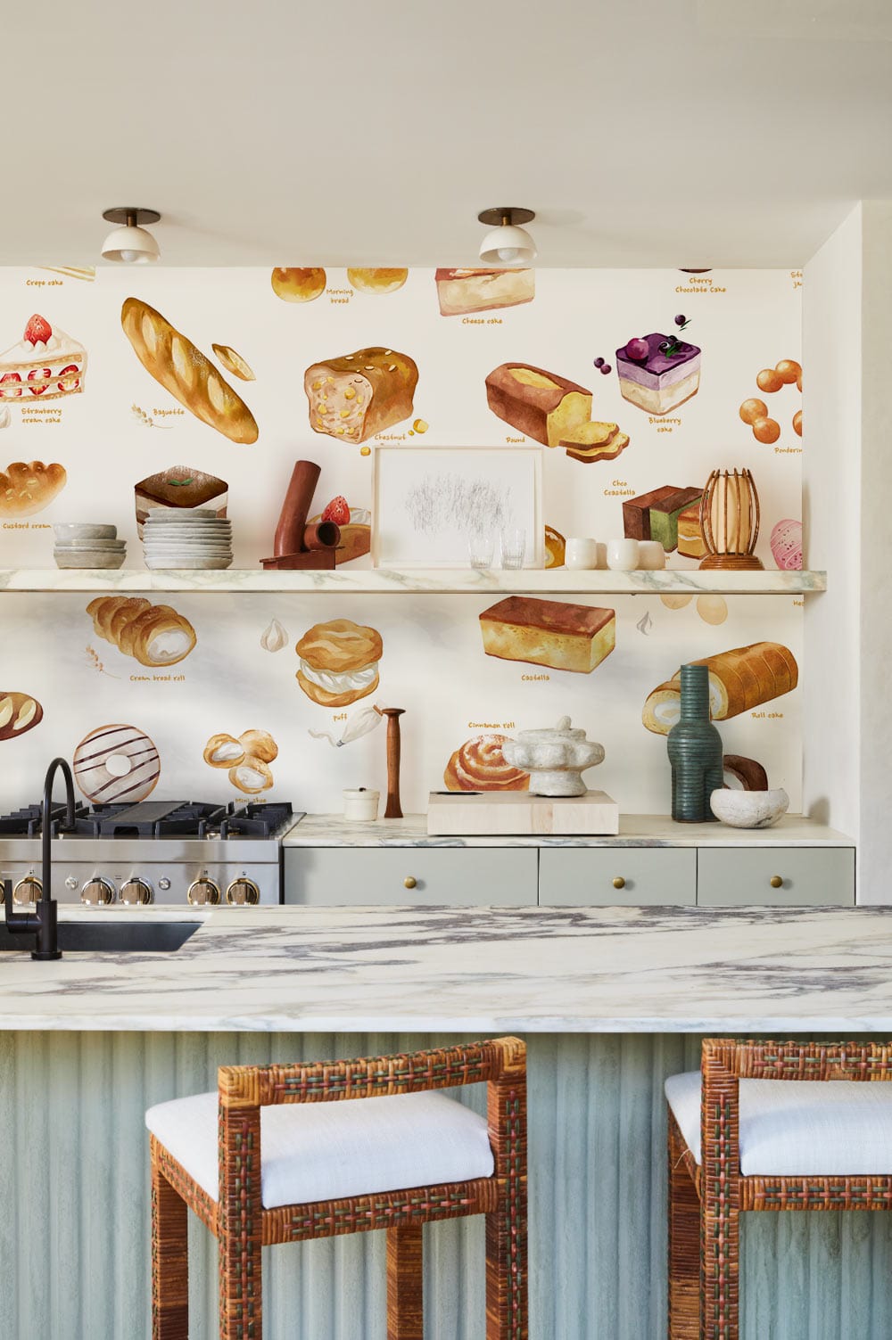 Artisan Bakery Treats Wallpaper in kitchen with patterned countertop, wicker stools, and open shelving.