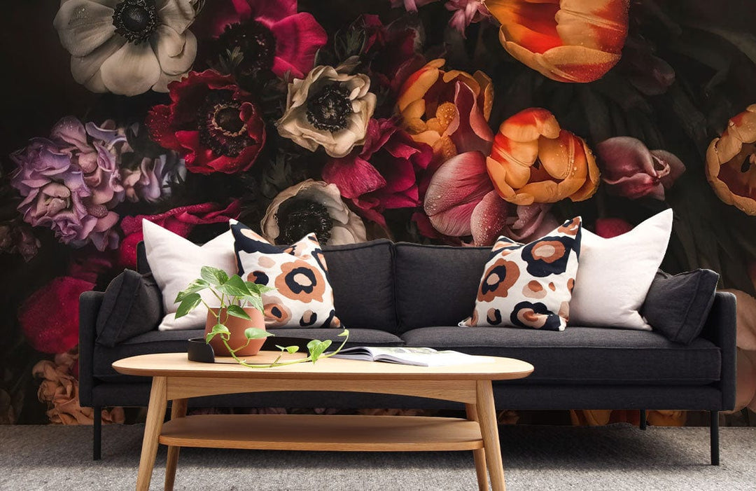 Elegant dark floral wallpaper in multicolour botanical design, dark sofa, light wood table, grey carpet.