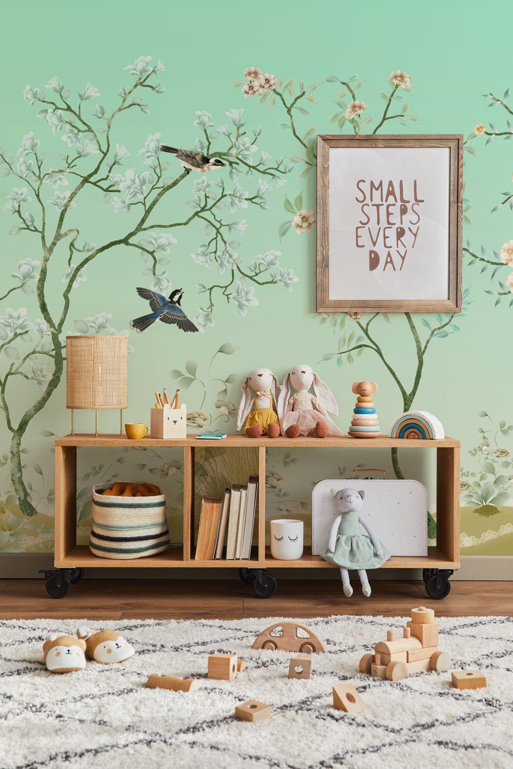 Mint green floral and bird wallpaper, natural wooden unit, nursery, cosy rug, inspiring wall art.