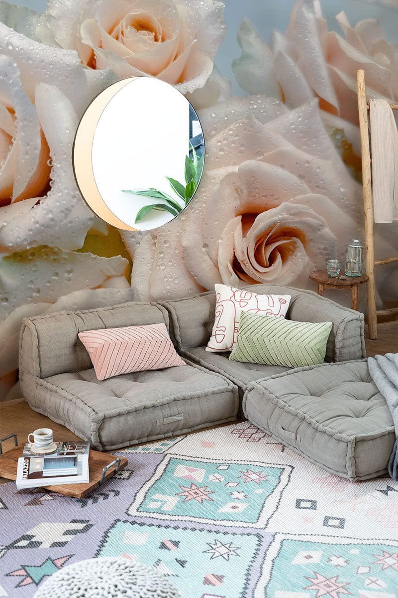 Elegant cream rose wallpaper, soft hues, grey modular sofa, patterned rug, round mirror in living room.