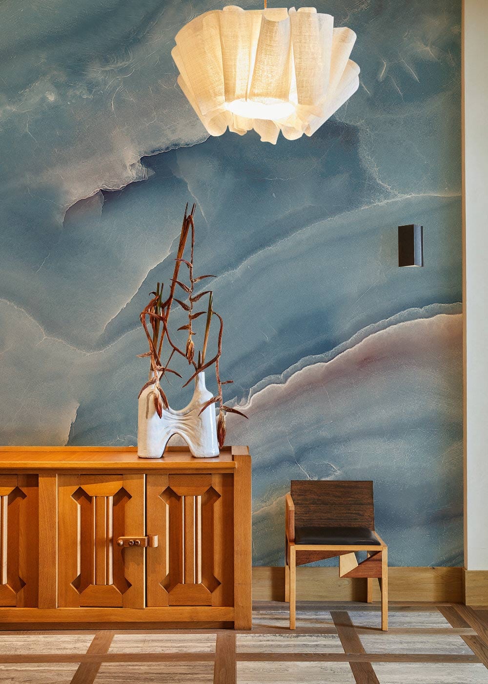 Elegant Blue Marble Effect Mural Wallpaper, soft pastel hues, wooden sideboard, modern chair, pendant light.