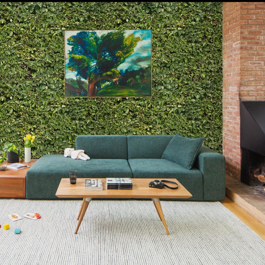 Verdant Green Foliage Wallpaper in living room with a teal sofa, artistic painting, and brick fireplace.