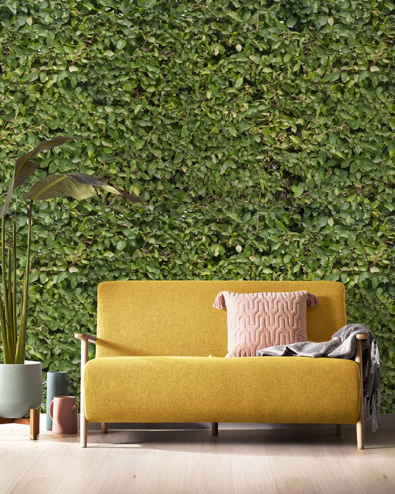 Yellow sofa in living room with Verdant Green Foliage wallpaper, plant decor, light wooden flooring.