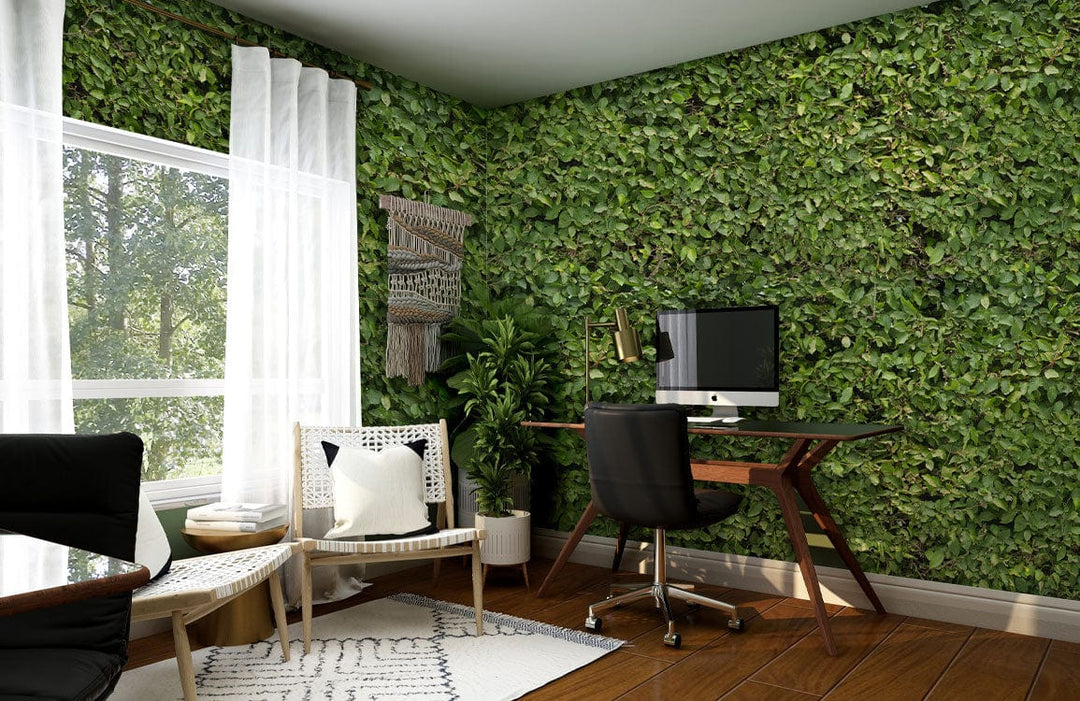 Verdant green foliage wallpaper with wooden desk, white chair, hardwood flooring, home office setting, nature decor.