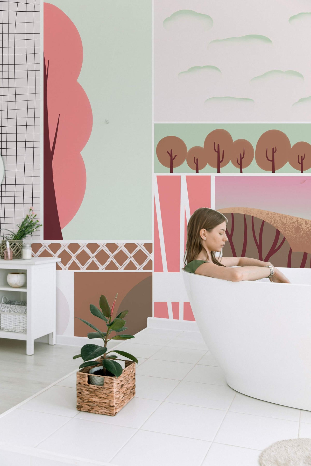 Pastel geometric landscape mural wallpaper in bathroom with modern white bathtub and wicker plant basket.